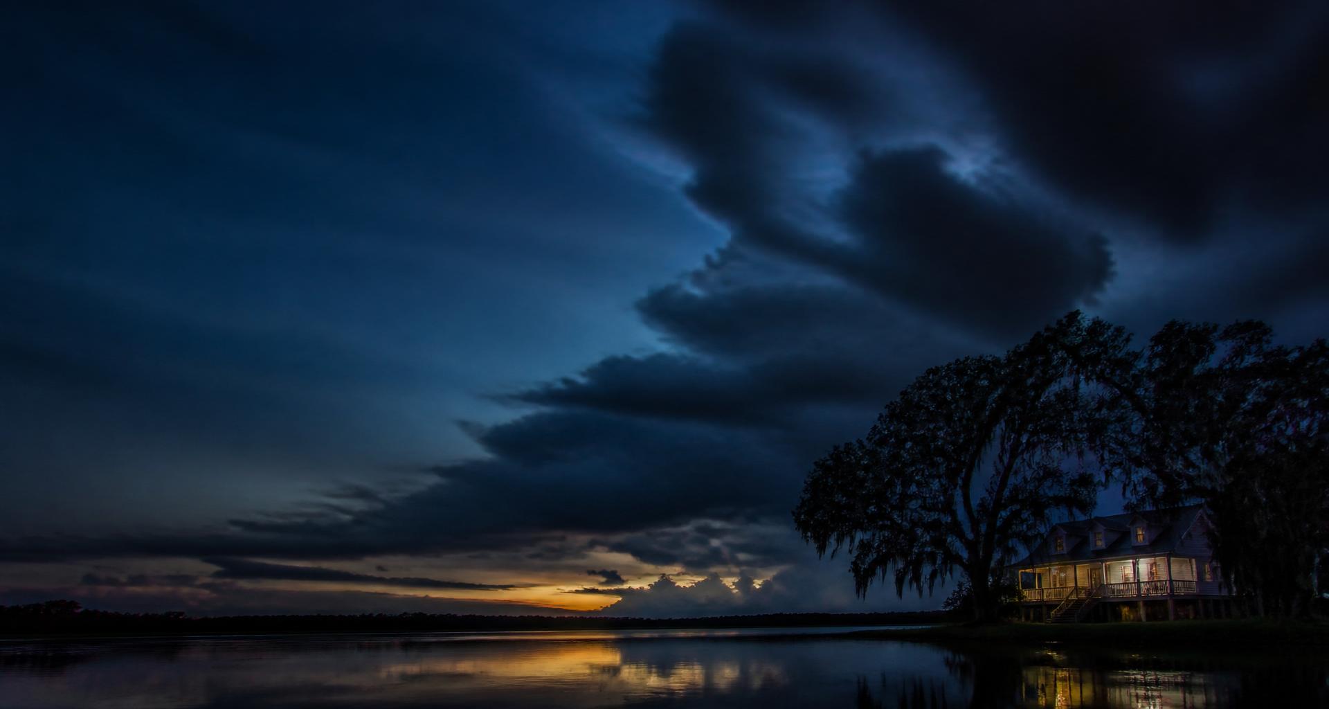 Heavy Gulf storm sky over low-lying Louisiana bayou landscape with a raised home